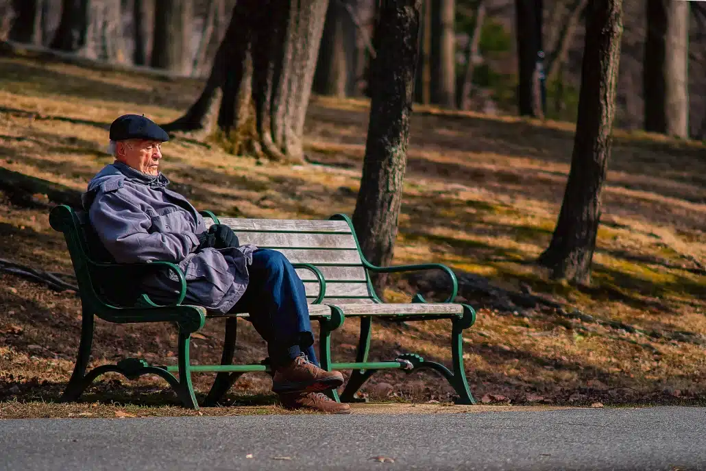 Old man sitting on a wooden bench in the forest