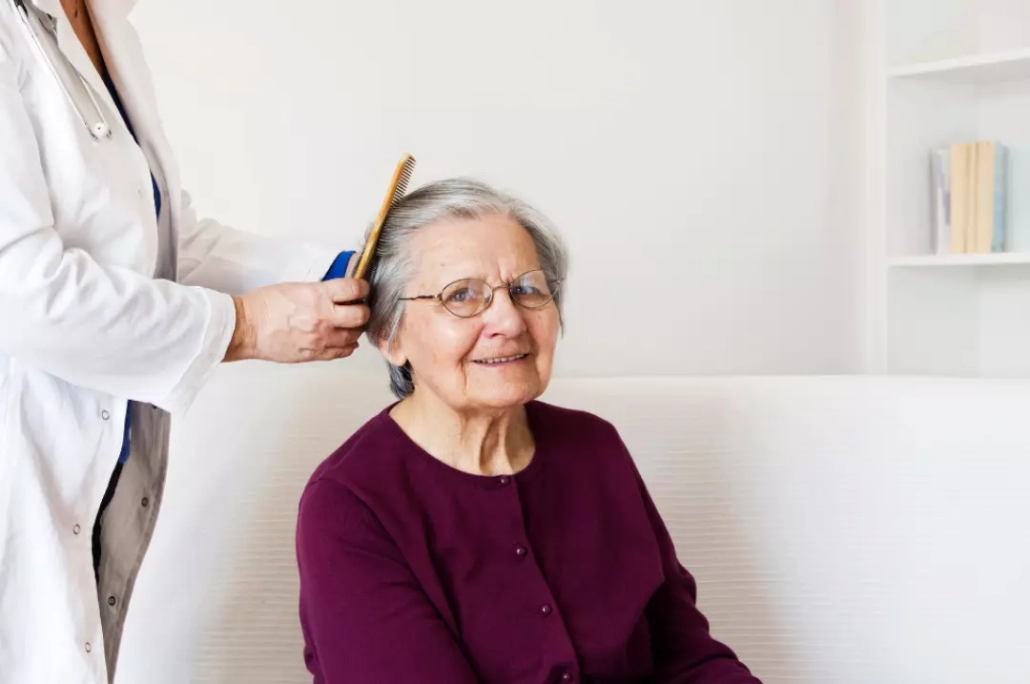 Caregiver combing elderly person's hair