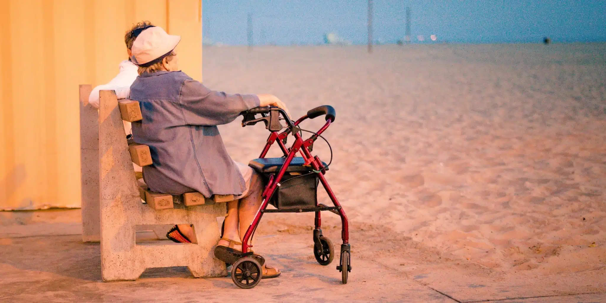 Elderly woman talking with another person while sitting on the bench on the seashore