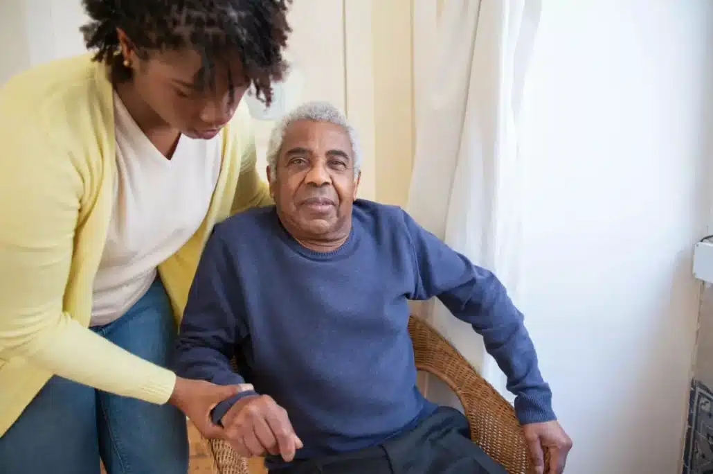 Caregiver helping senior man stand up