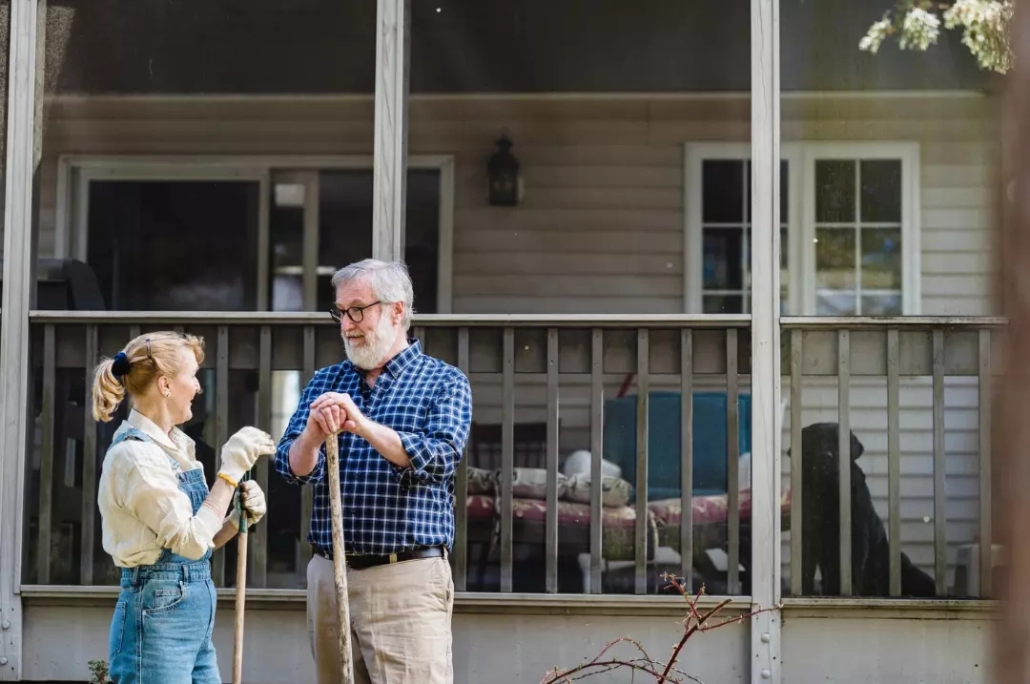 Old couple talking with each other while holding gardening tools