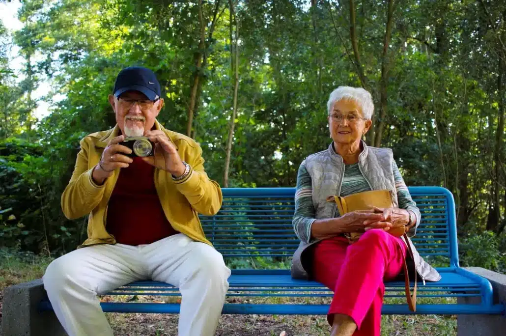 Senior couple sitting on a blue metal bench.