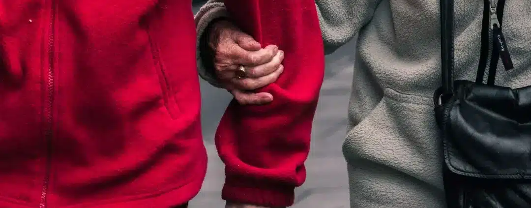 Senior couple wearing red and gray jacket.