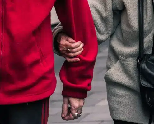 Senior couple wearing red and gray jacket.