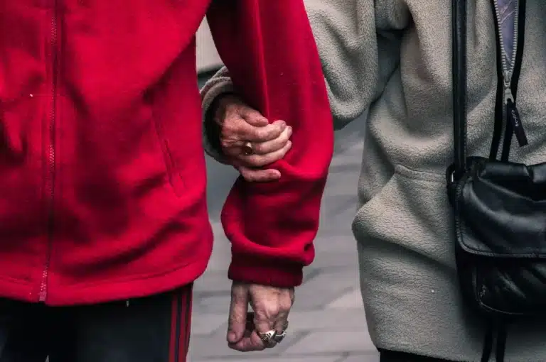 Senior couple wearing red and gray jacket.