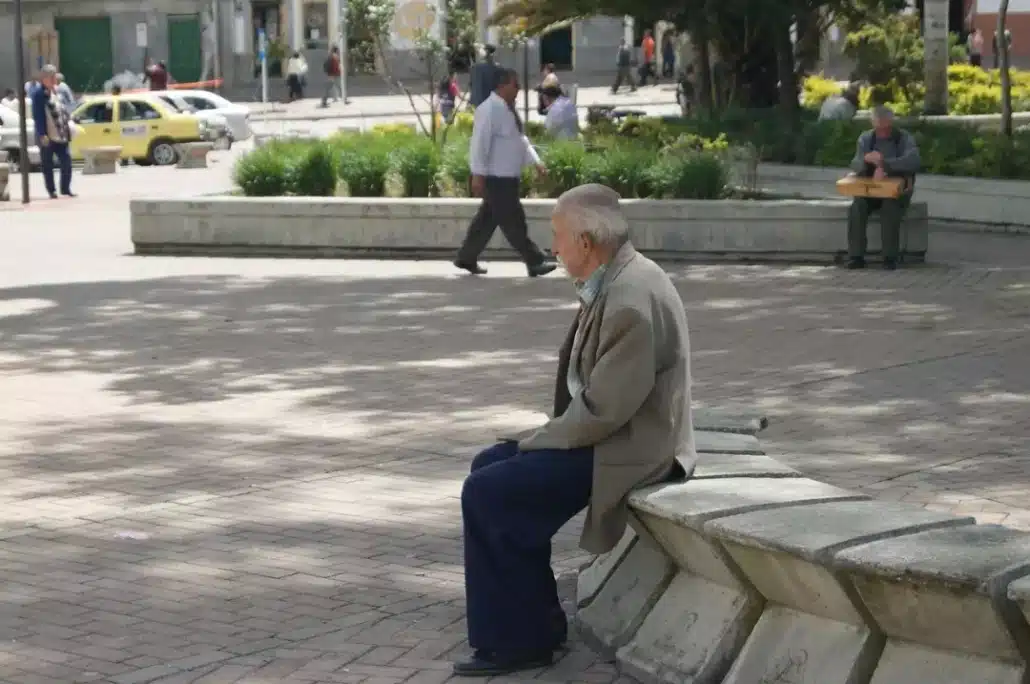 Senior man sitting alone on a concrete bench in the park.