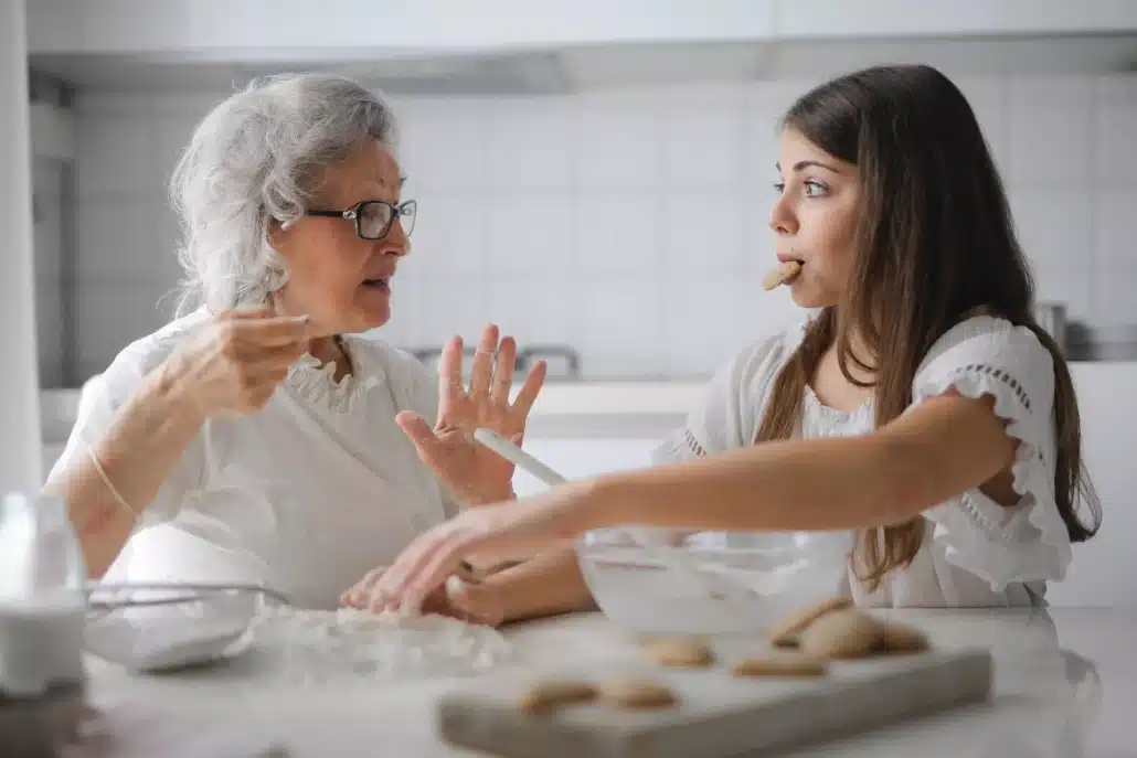 Grandmother and granddaughter baking cookies in the kitchen.