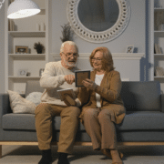 Elderly couple sitting on a couch while looking at the framed pictures.