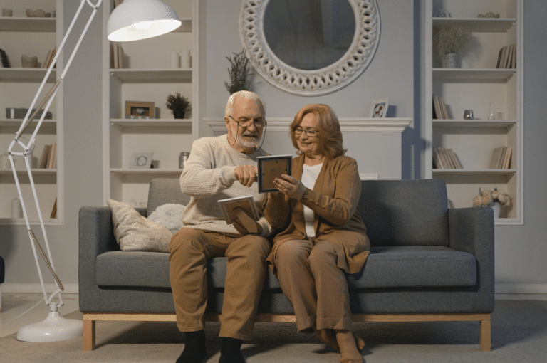 Elderly couple sitting on a couch while looking at the framed pictures.