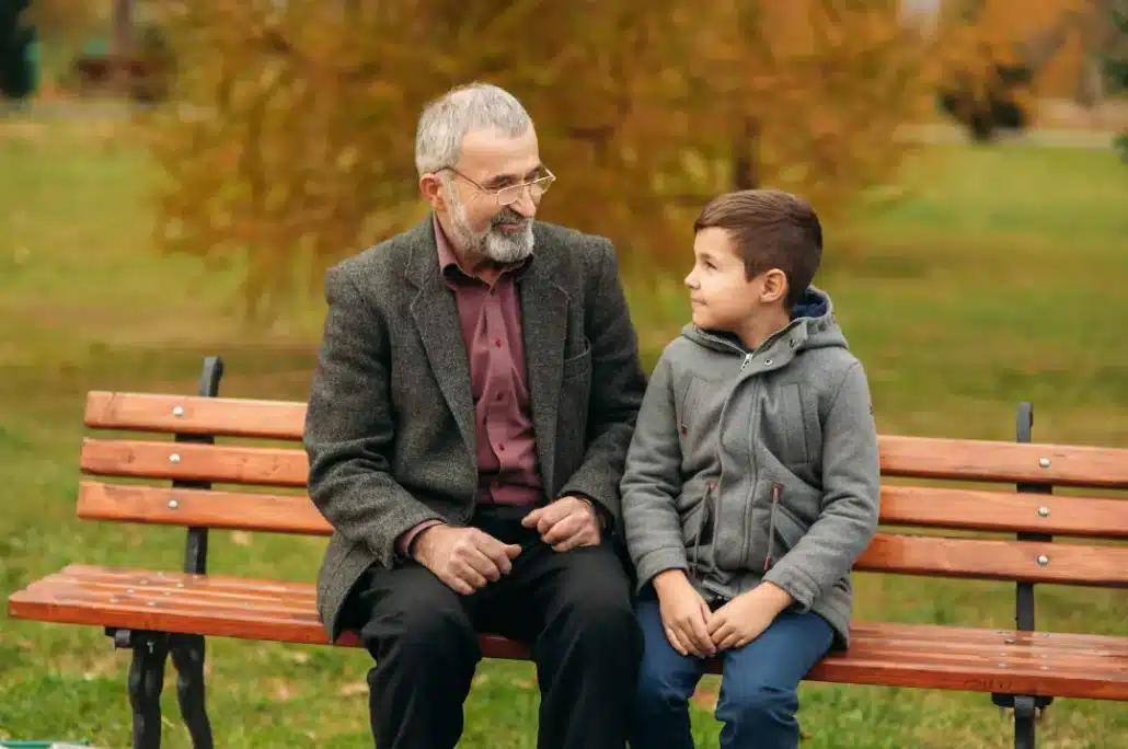 Grandfather and grandson sitting together on a wooden bench.