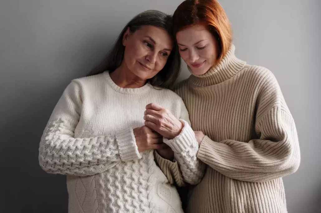 Mother and daughter wearing knitted sweaters.