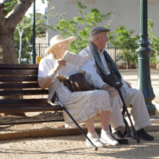 Senior couple sitting on a black metal bench in the park.