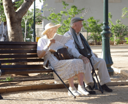 Senior couple sitting on a black metal bench in the park.