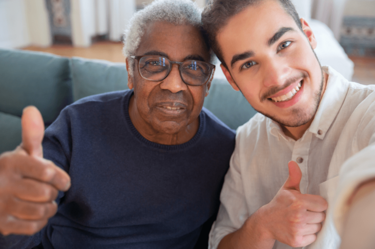 Carer and an old man smiling and doing a thumbs up.