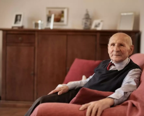 Old man sitting on a red sofa.