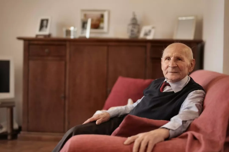 Old man sitting on a red sofa.