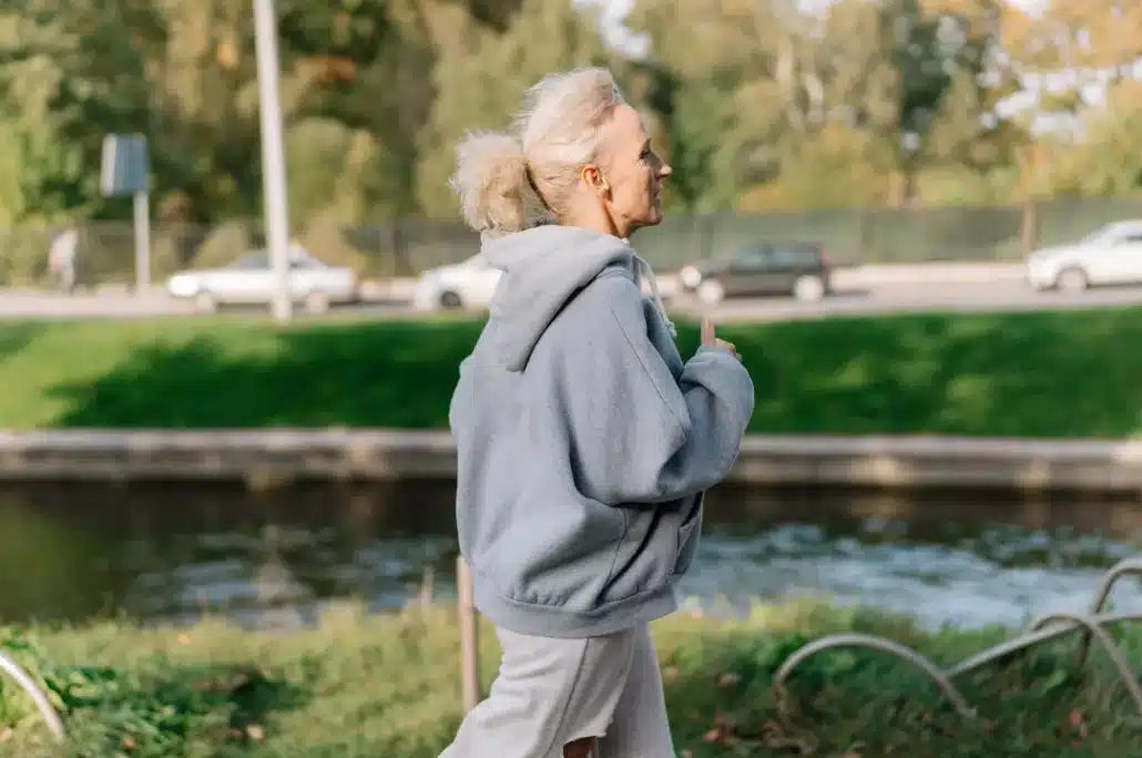 Old woman in gray jacket jogging.