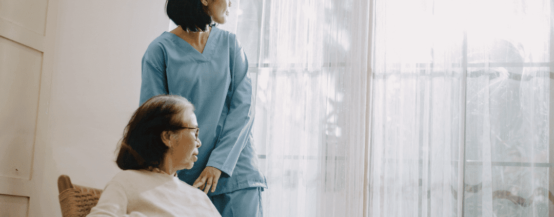 Elderly woman in a rocking chair receiving a home care package from a carer.