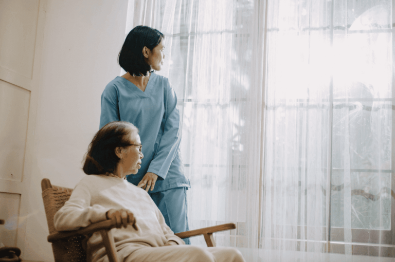 Elderly woman in a rocking chair receiving a home care package from a carer.