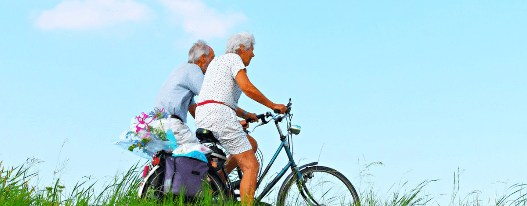 Senior couple promoting healthy ageing by biking together.