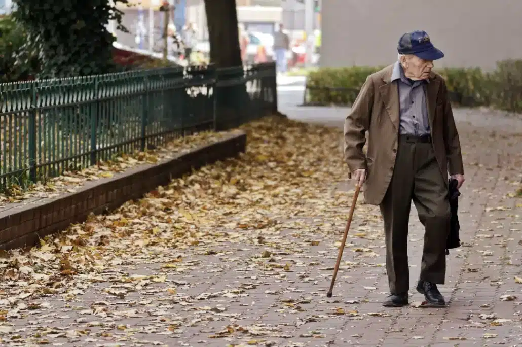 Senior man walking on pavement.