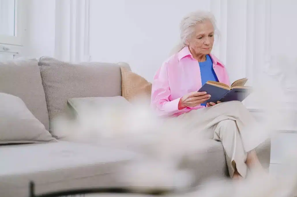 Senior woman reading a book while sitting on a sofa.