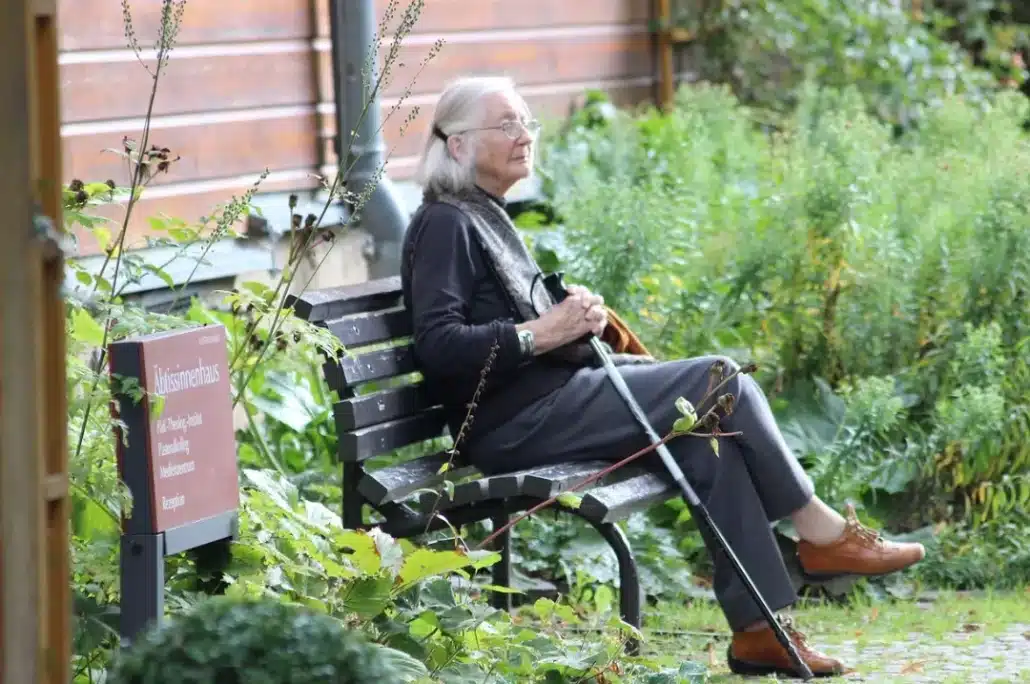 Senior woman sitting on a brown metal bench.