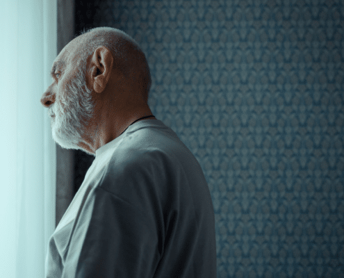 Sad elderly man looking at the window.