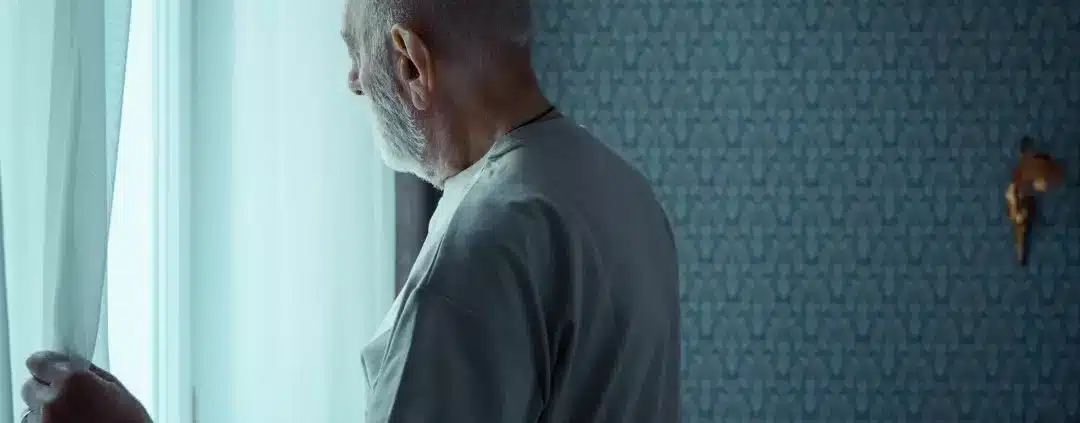 Old man opening a window curtain.