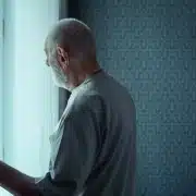 Old man opening a window curtain.