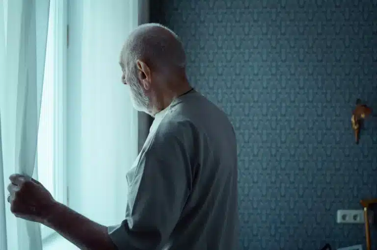 Old man opening a window curtain.