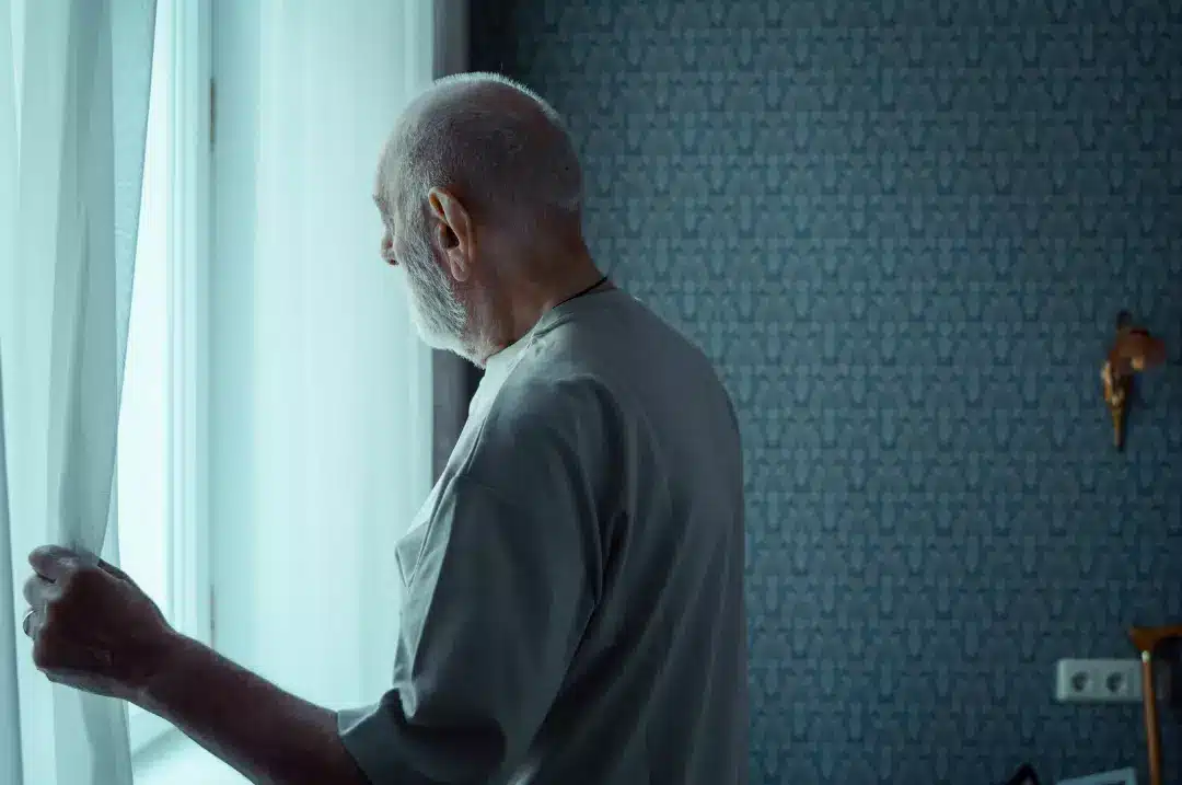 Old man opening a window curtain.