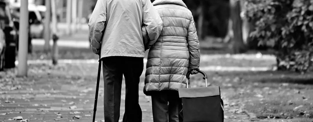 Grayscale picture of an elderly couple walking together.