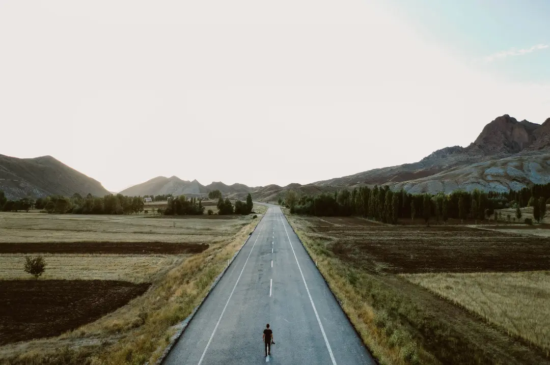 A person standing alone in the middle of the concrete road.